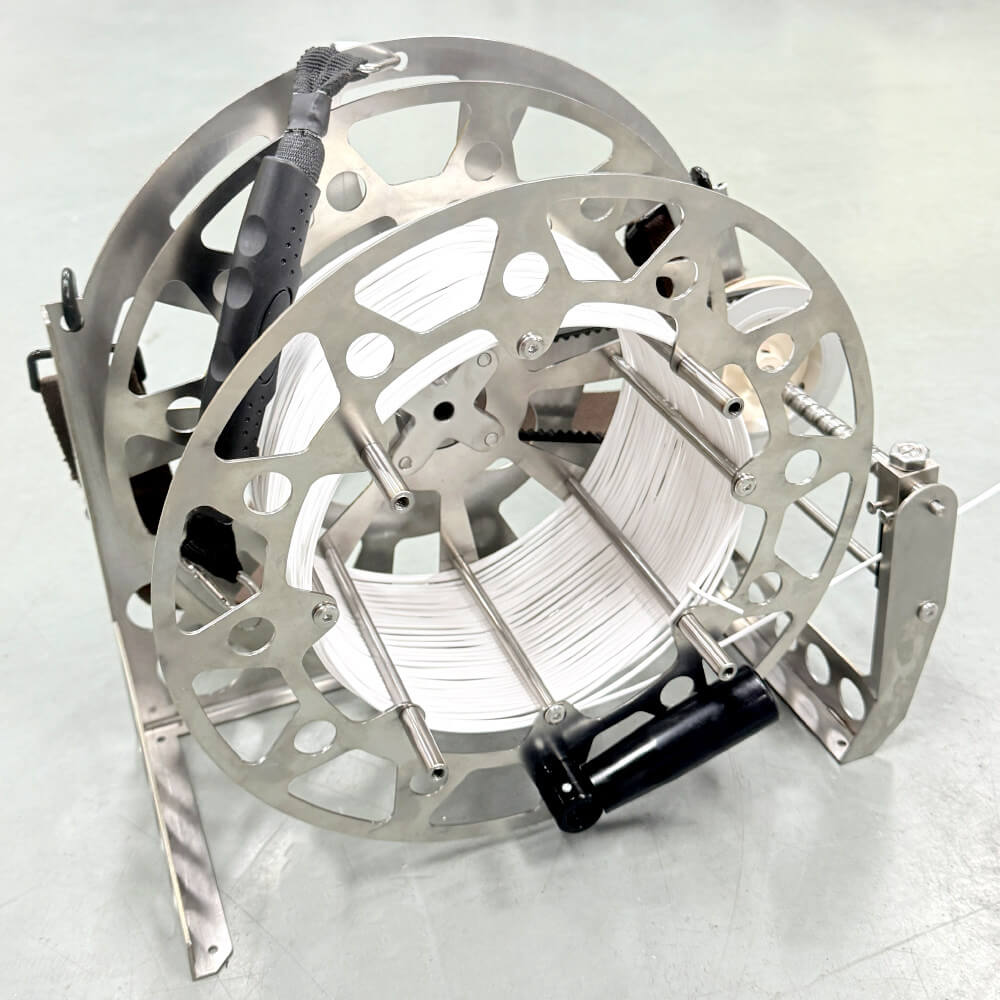 Hand-crank subsea tether reel spooled with optical fiber cable featuring foldable handle and ground frame